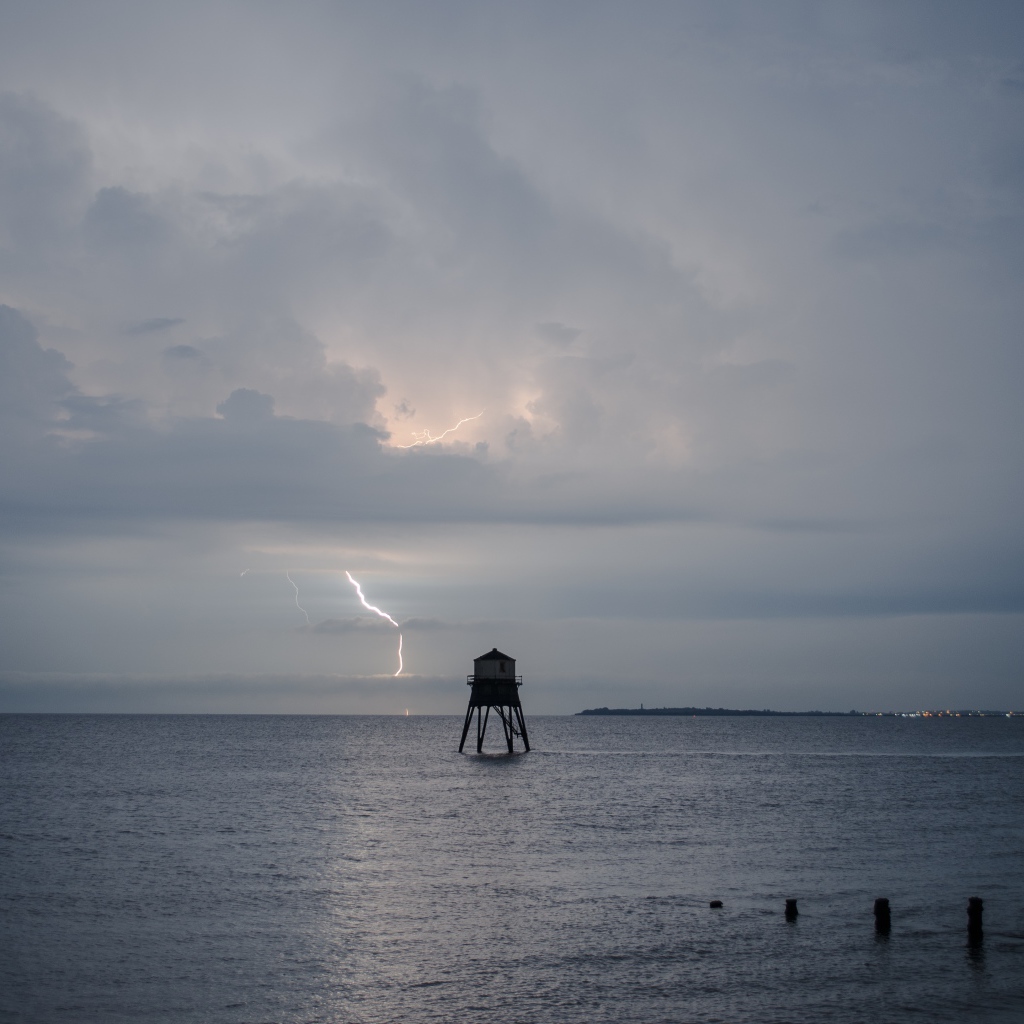 Старая башня в море на фоне грозы 