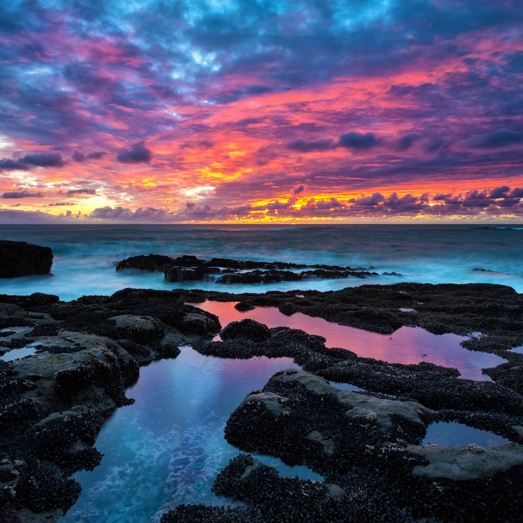 Восход яркого солнца над камнями в море