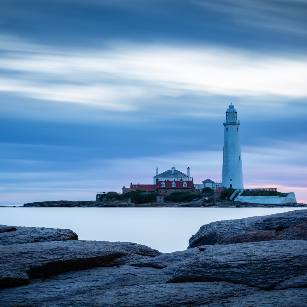 Вид с каменного берега на маяк в море 