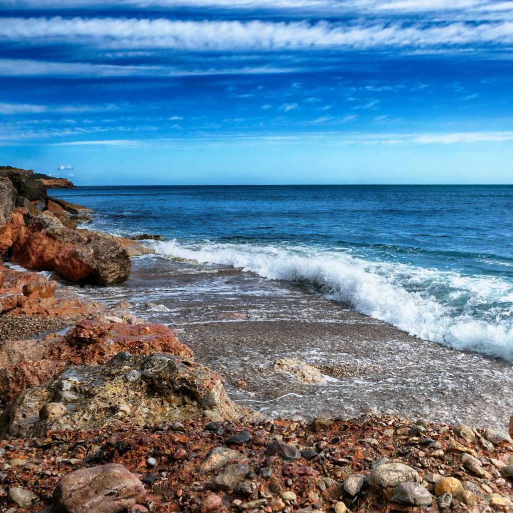 Белые волны на берегу моря с большими камнями под голубым небом