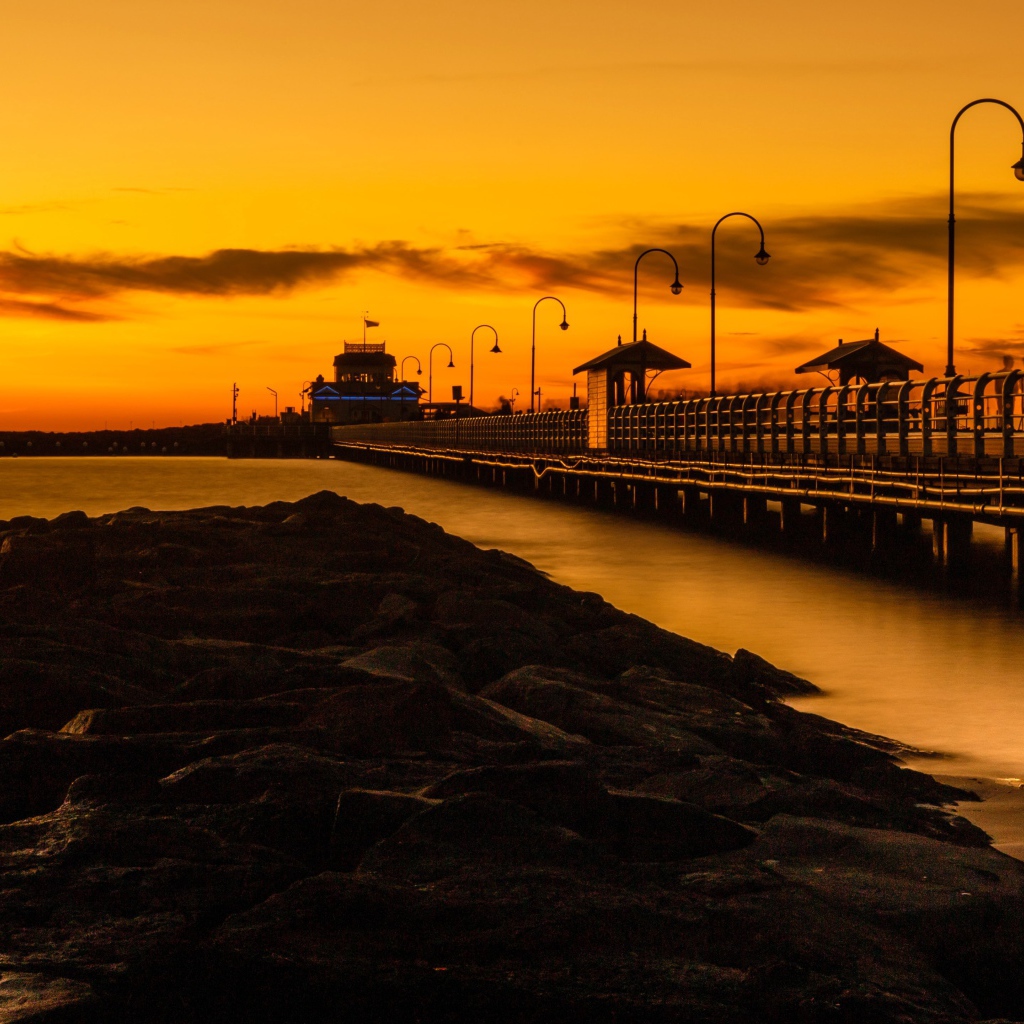 Длинный мост на морском побережье на закате 