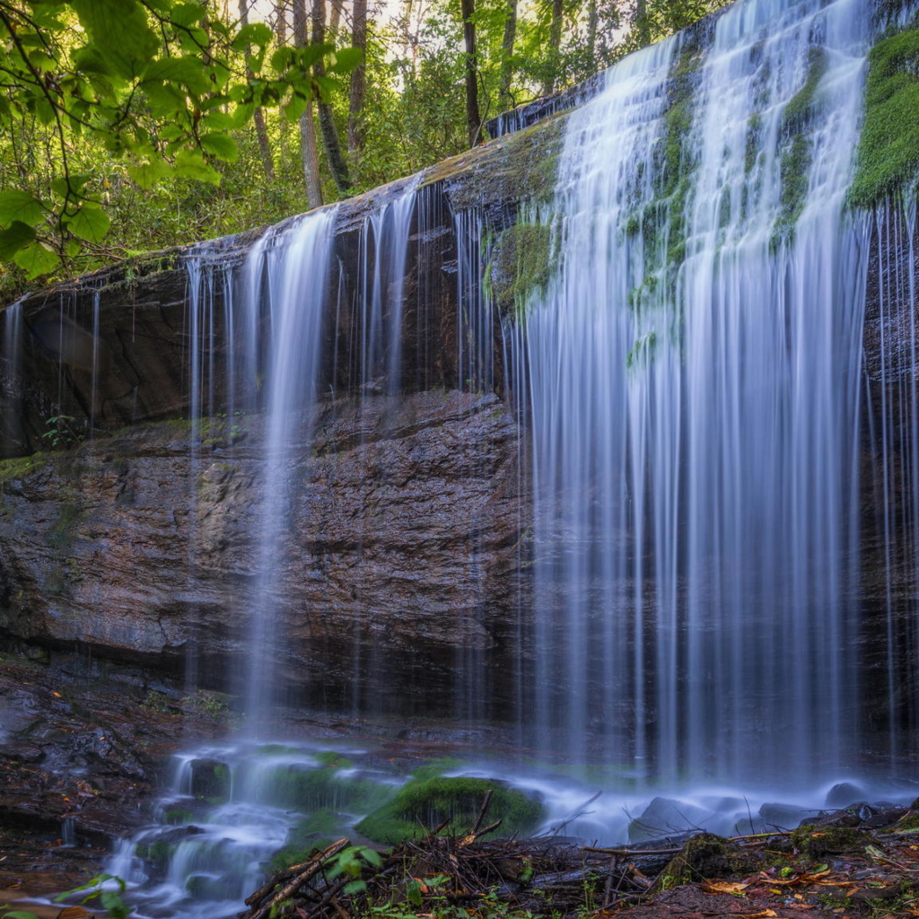 Холодная вода водопада стекает по мокрой скале