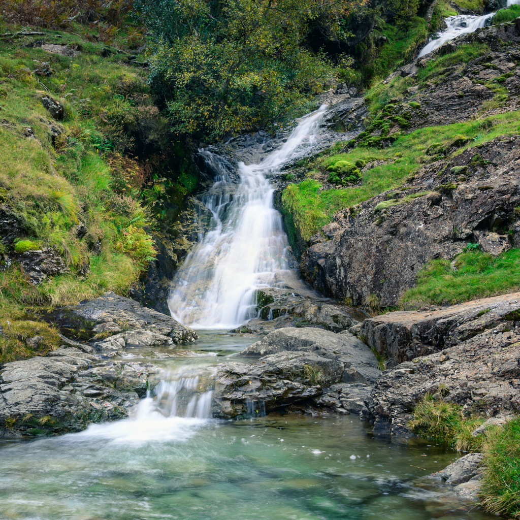 Горный ручей стекает по камням в реку 