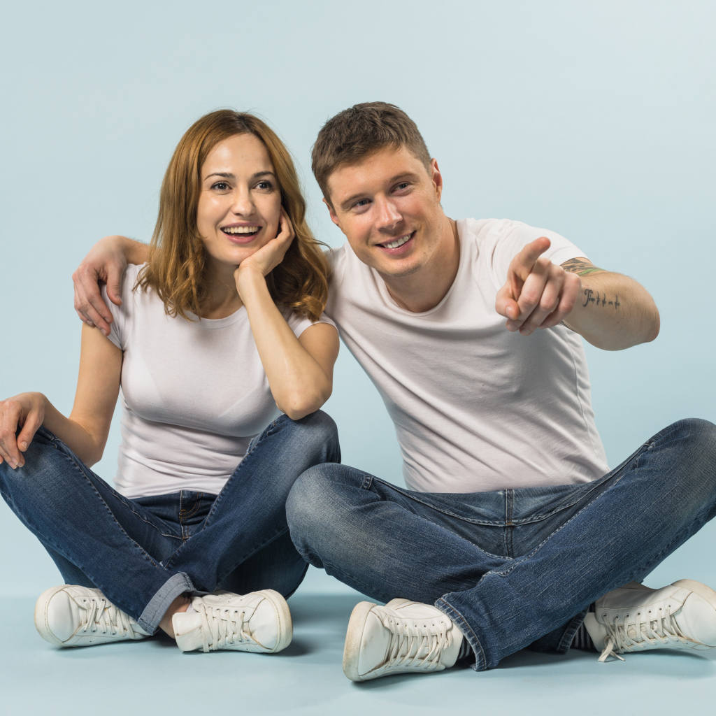 Мужчина и девушка сидят на полу на голубом фоне