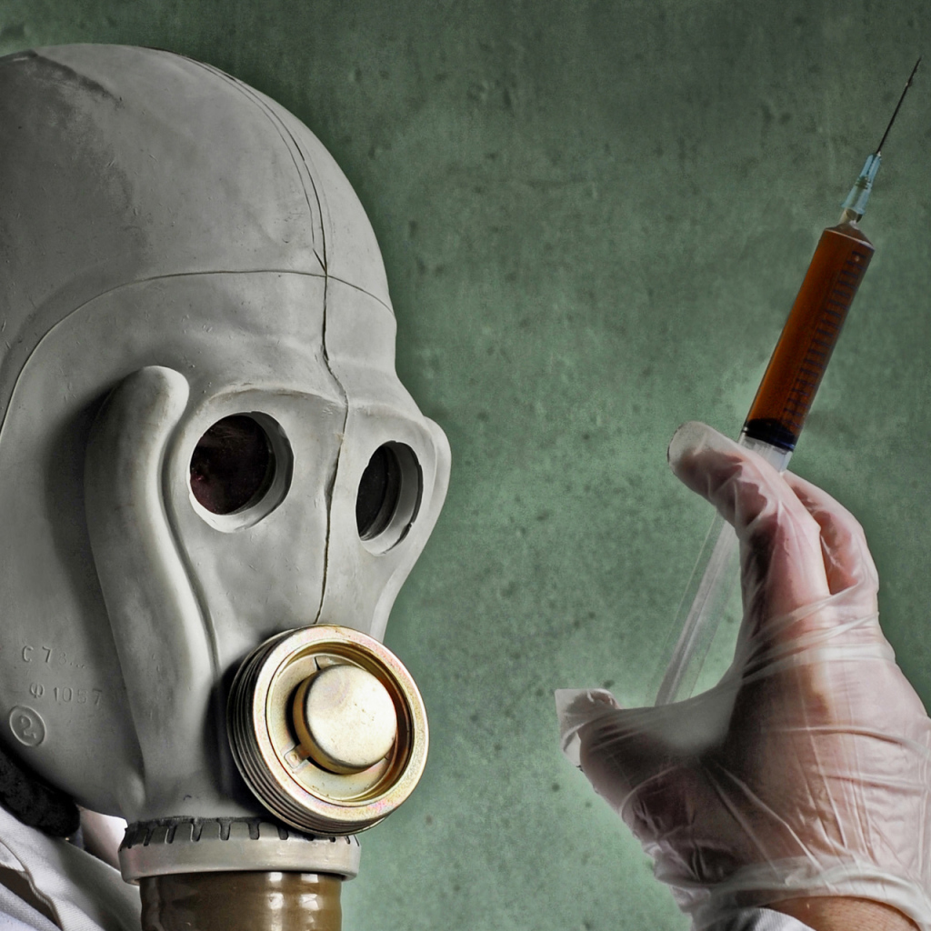 Мужчина в противогазе со шприцем в руках, пандемия коронавирус