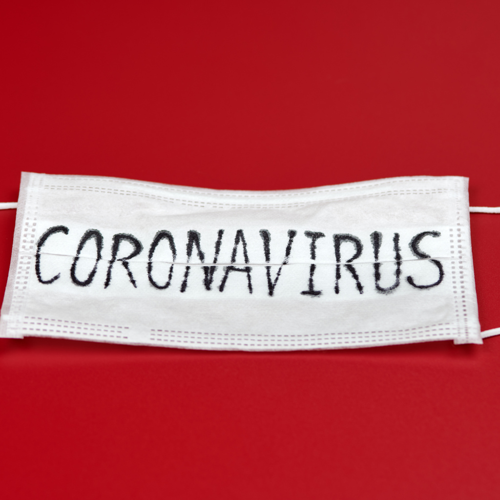 Медицинская маска с надписью коронавирус Covid-19 на красном фоне