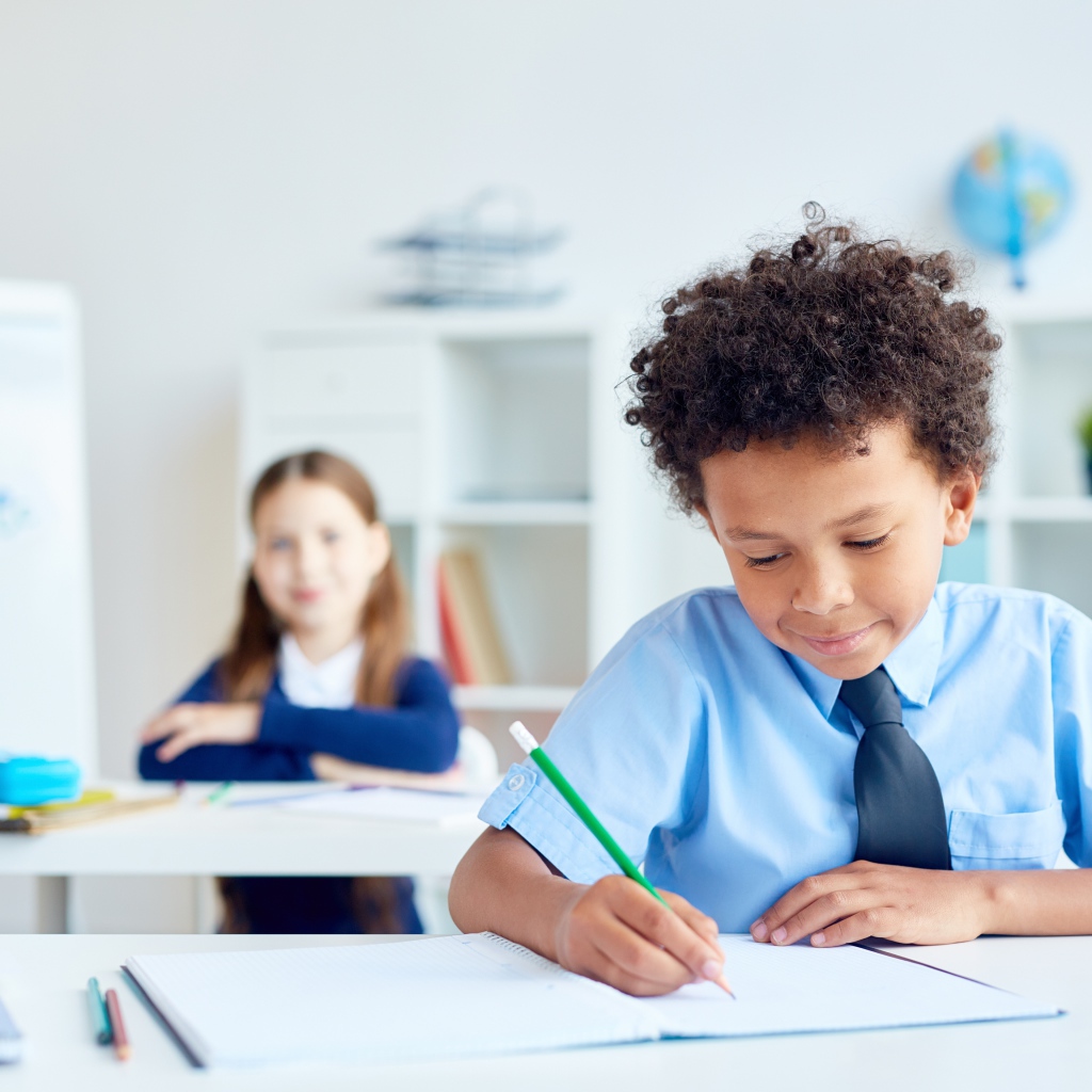 Маленький мальчик сидит за партой в классе