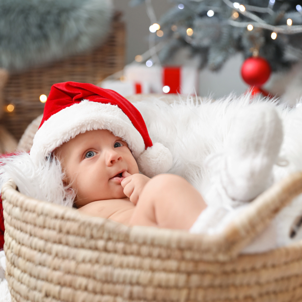 Милый малыш в шапке Санта Клауса лежит в корзине