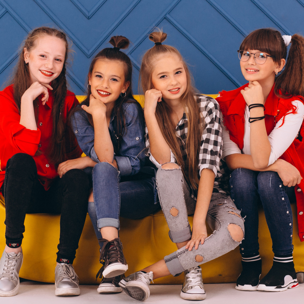 Четыре модных девочки сидят на диване 