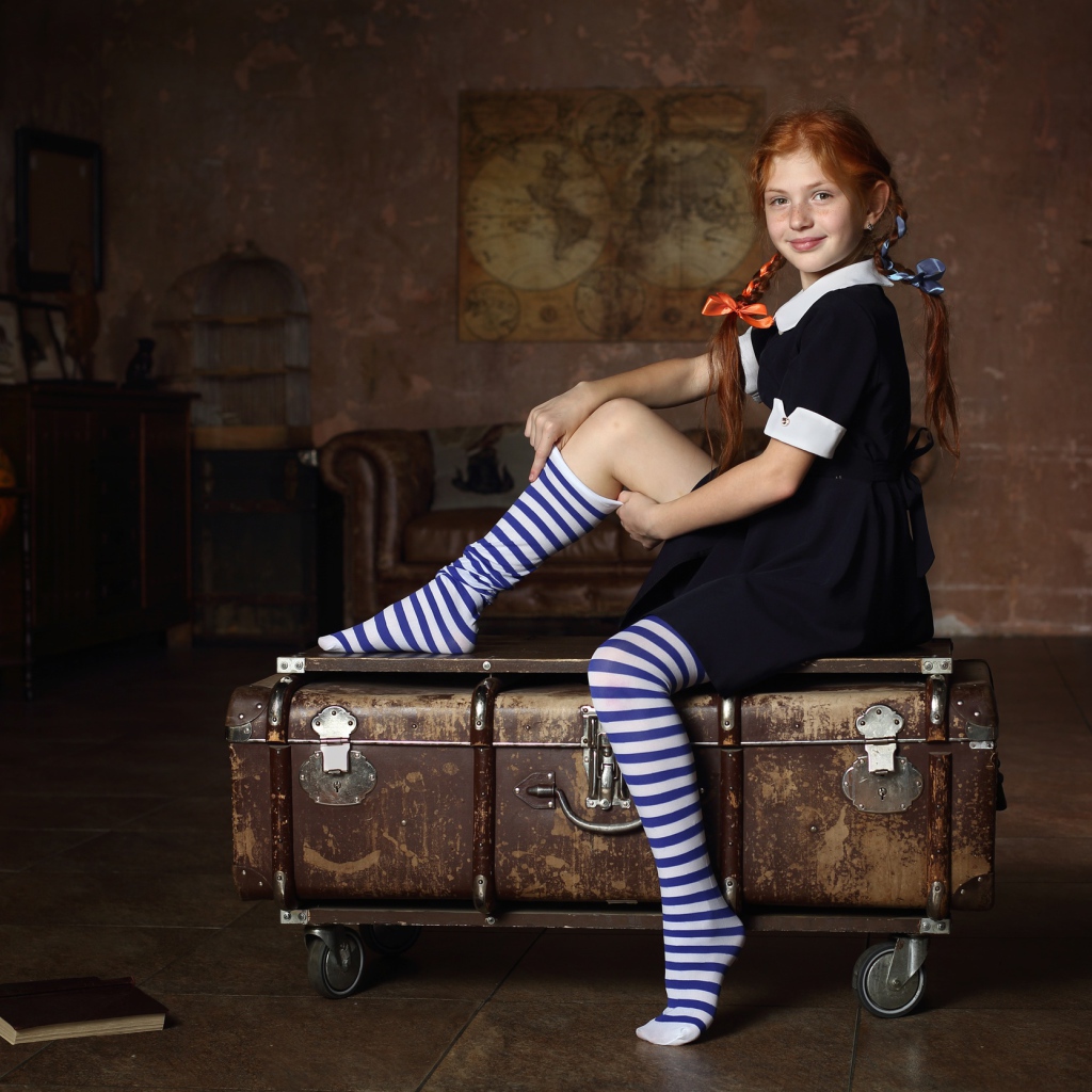 Девочка в школьной форме сидит на чемодане 