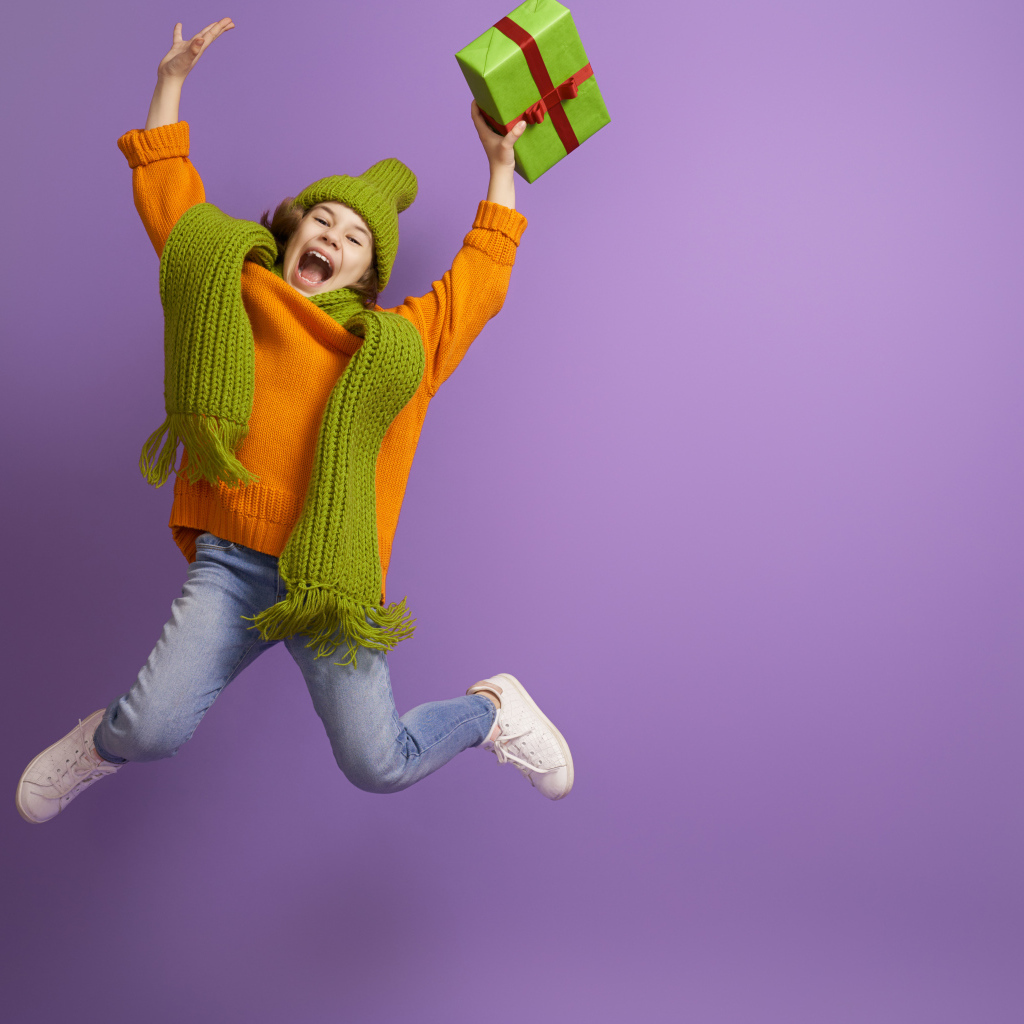 Счастливая девочка с подарком в руке на фиолетовом фоне