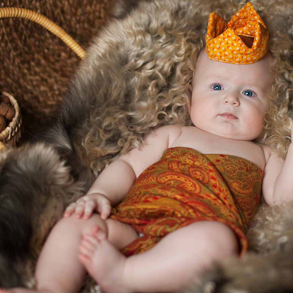 Маленький грудной ребенок в короне лежит в корзине 