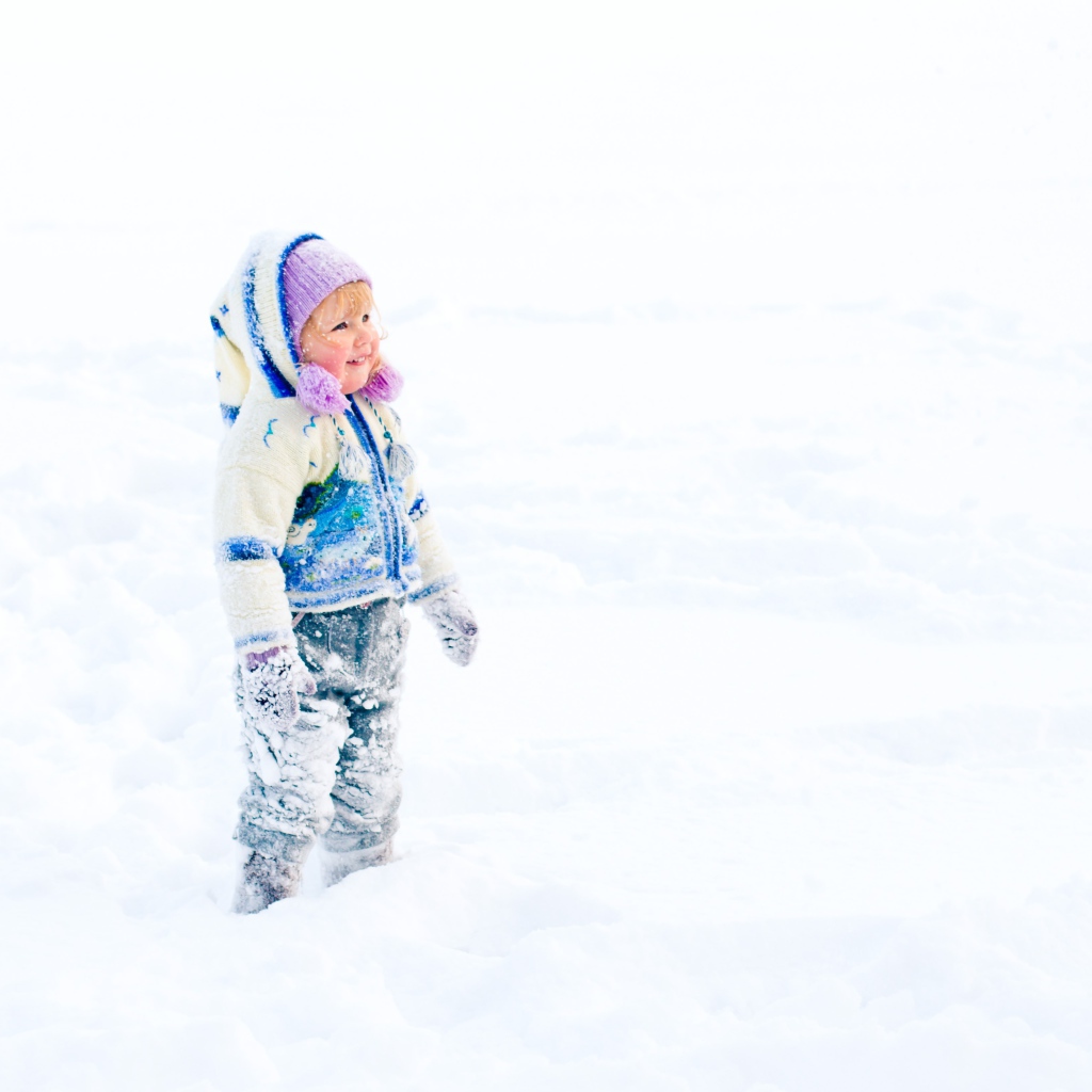Маленькая веселая девочка гуляет по снегу