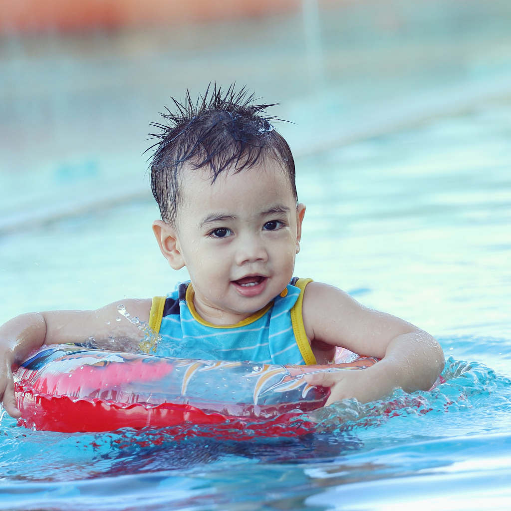 Маленький ребенок со спасательным кругом в бассейне 