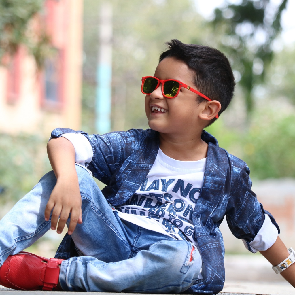 Маленький модный мальчик сидит на асфальте