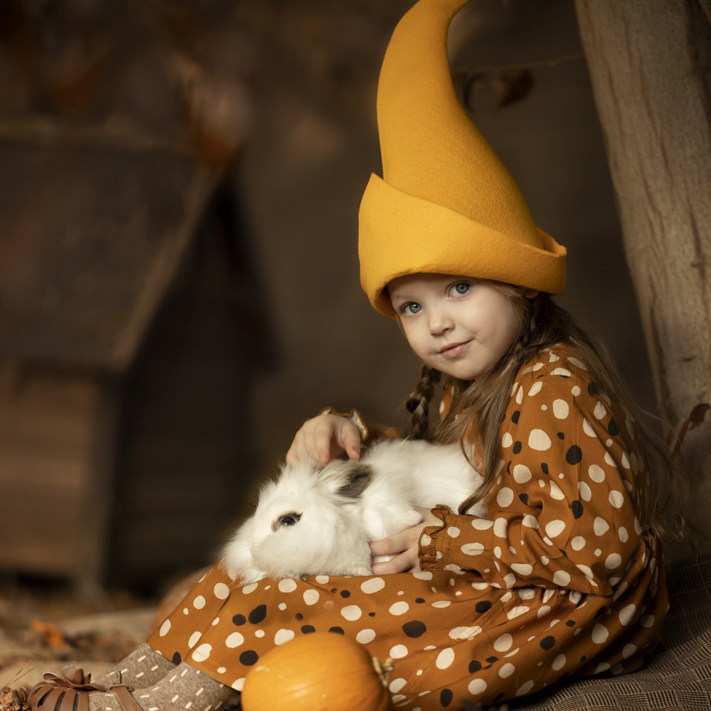 Маленькая смешная девочка в колпаке с кроликом