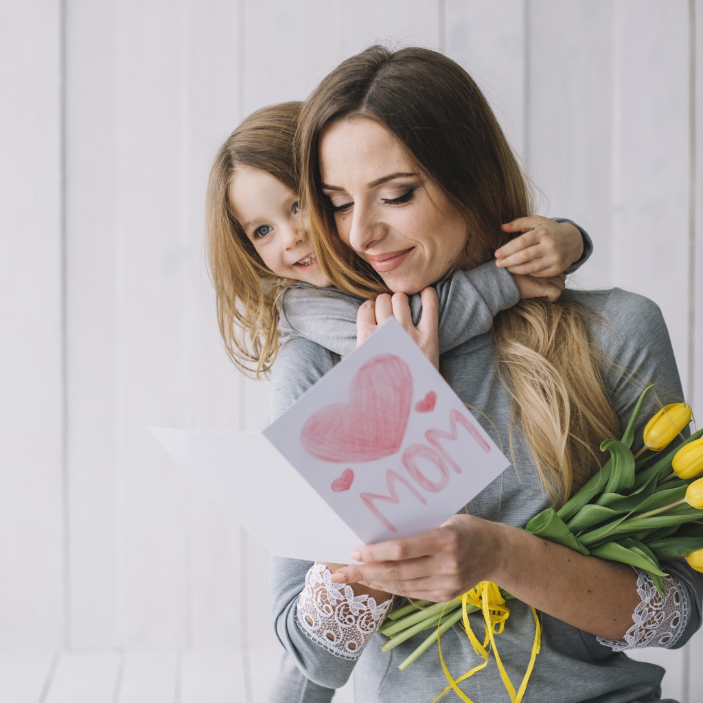 Маленькая девочка подарила маме открытку и букет тюльпанов