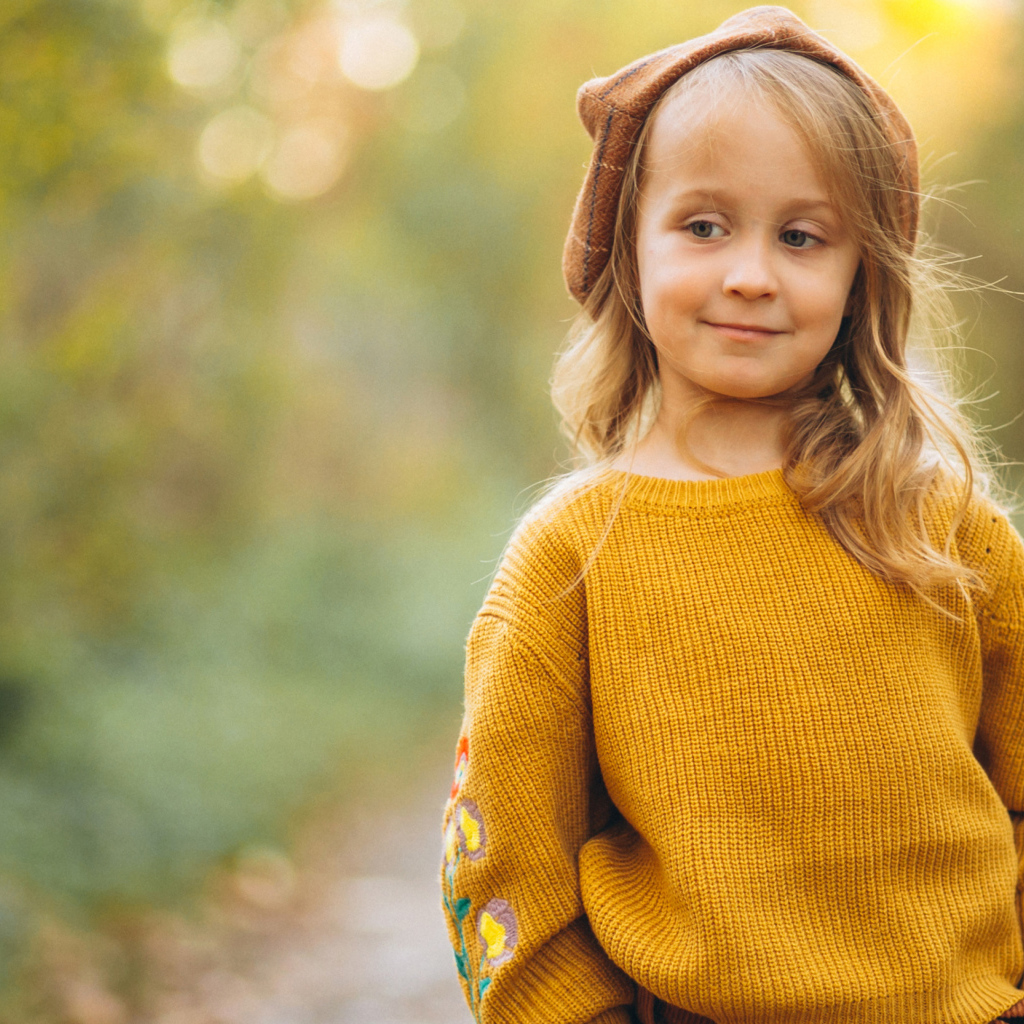 Маленькая девочка в свитере гуляет в лесу