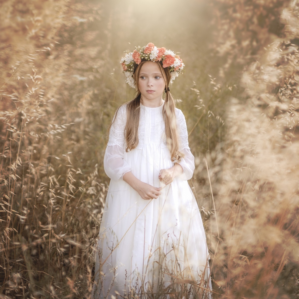 Маленькая девочка в белом платье с венком на голове 