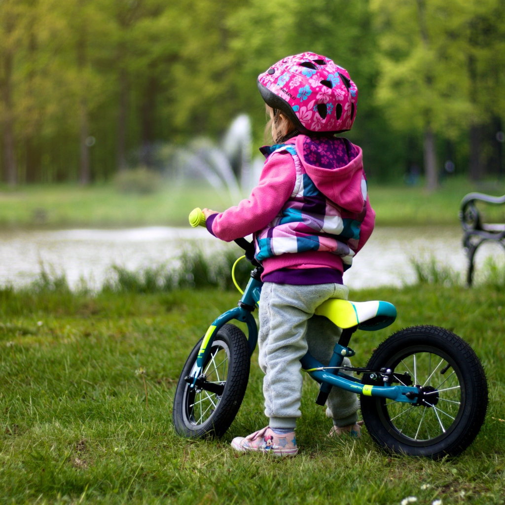 Маленькая девочка на велосипеде в парке 