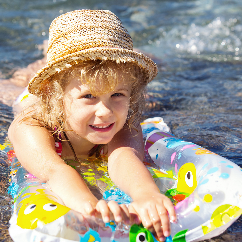 Маленькая девочка на надувном матрасе в воде
