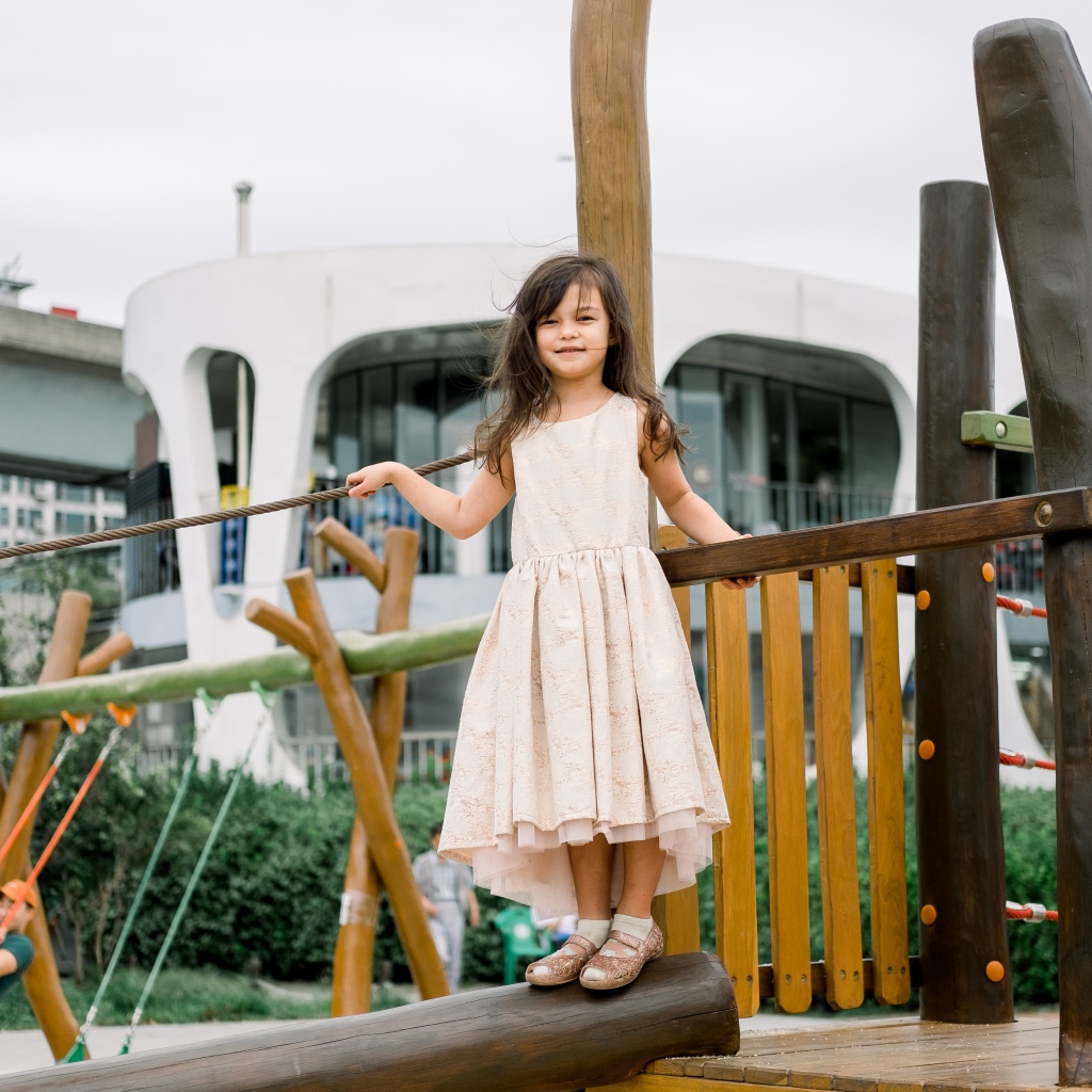 Маленькая девочка стоит на детской площадке 
