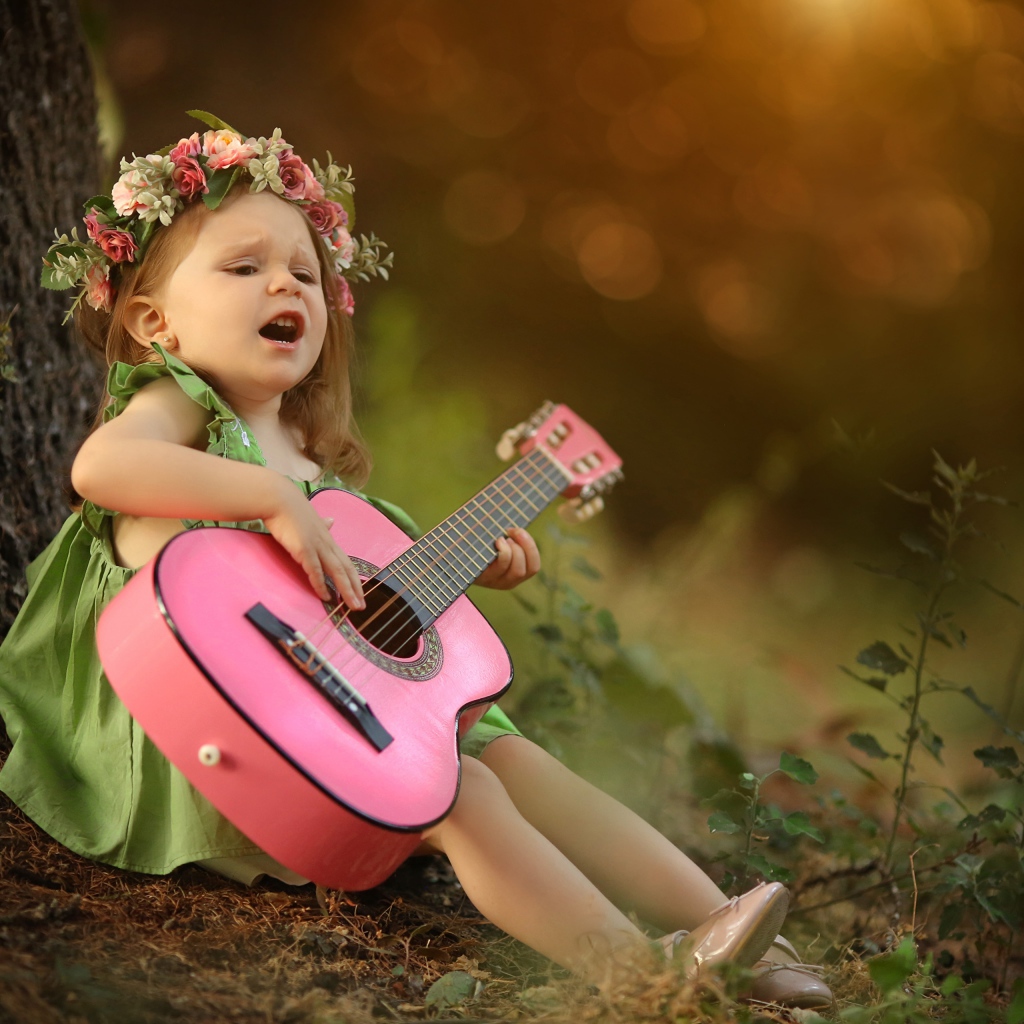 Маленькая девочка с гитарой под деревом 