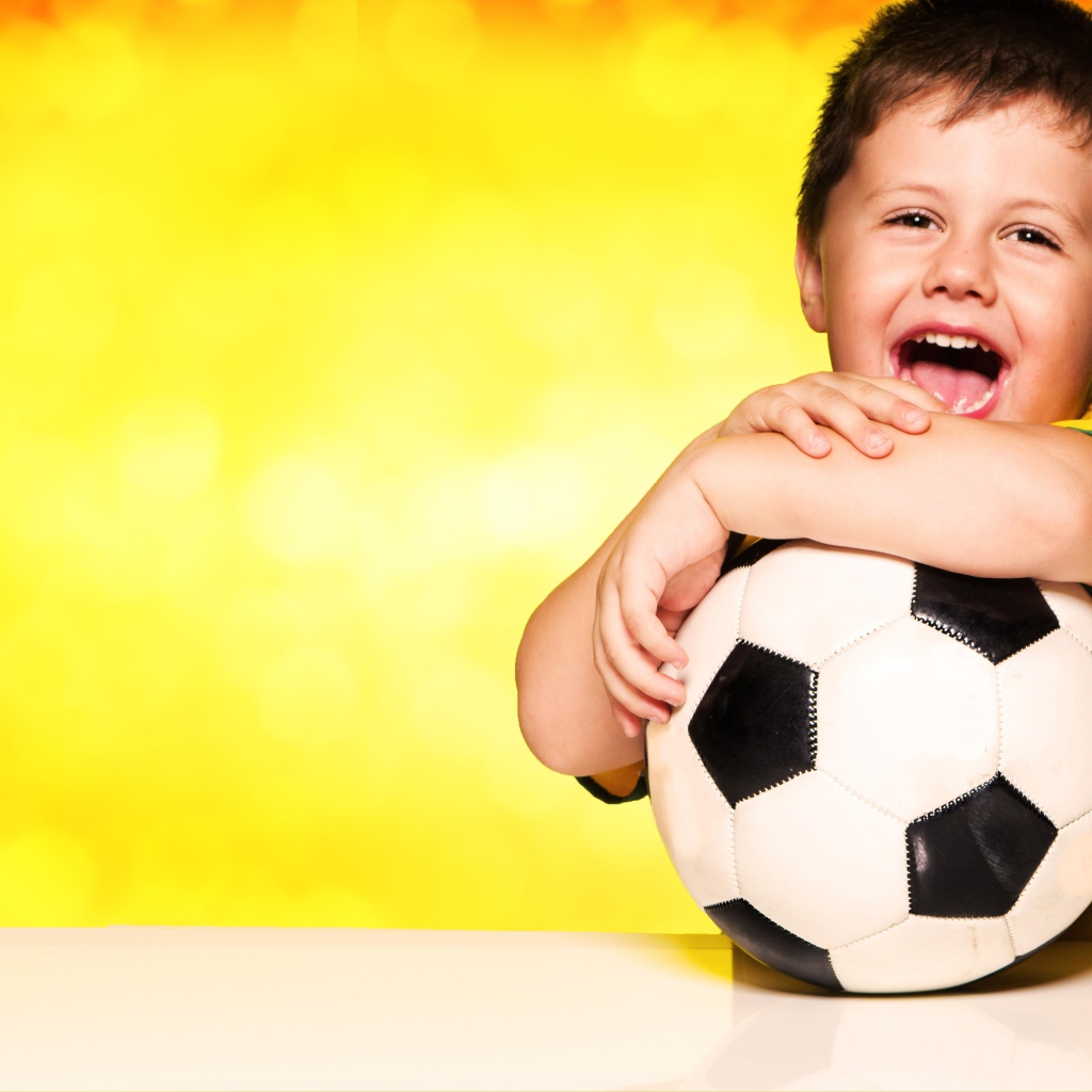 Маленький довольный мальчик с футбольным мячом