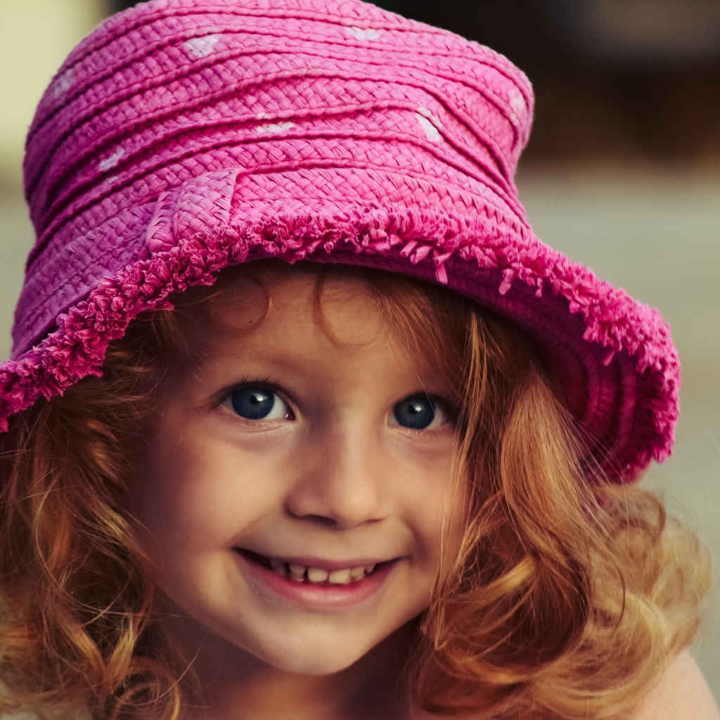 Маленькая улыбающаяся девочка в розовой шляпе
