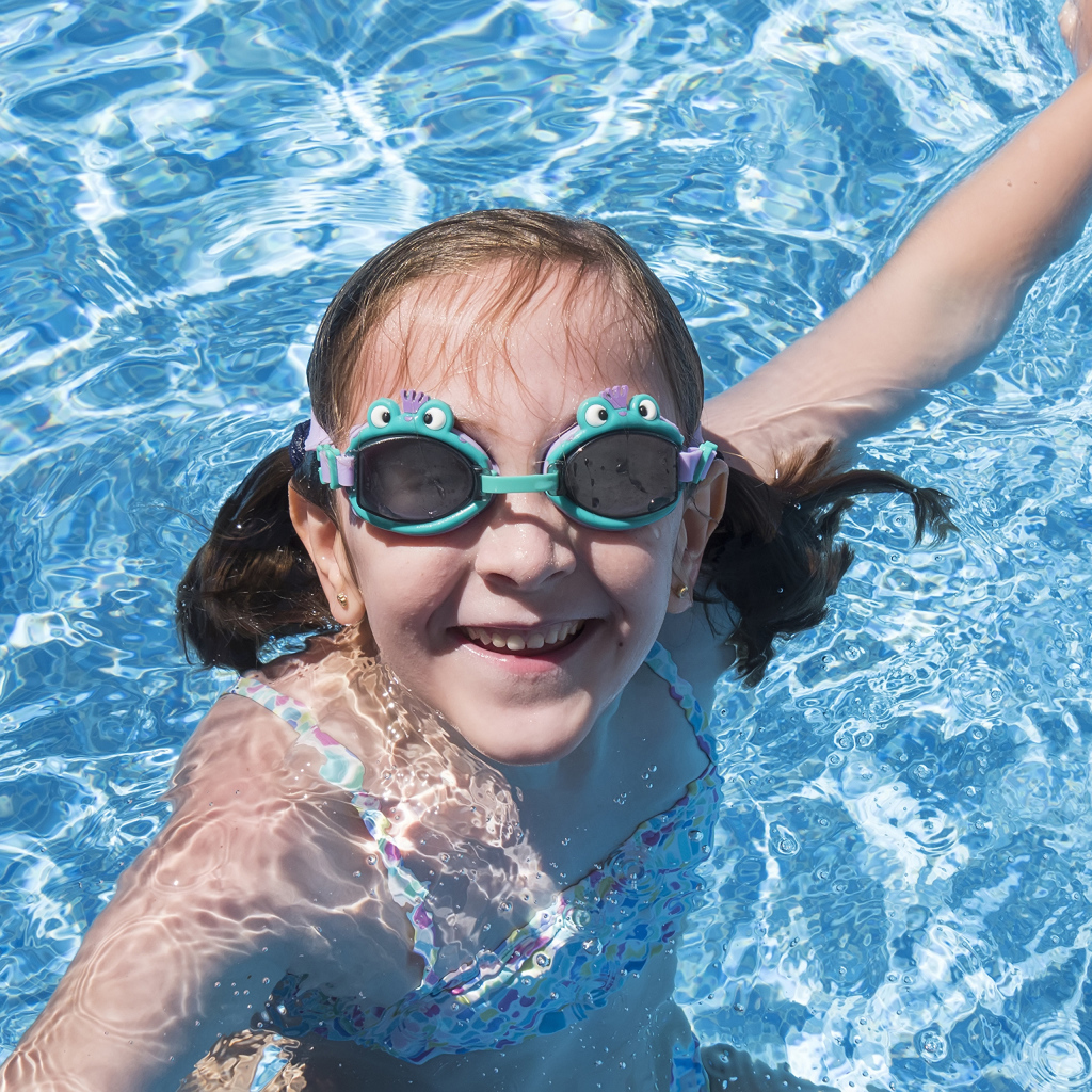 Маленькая улыбающаяся девочка в очках в бассейне 