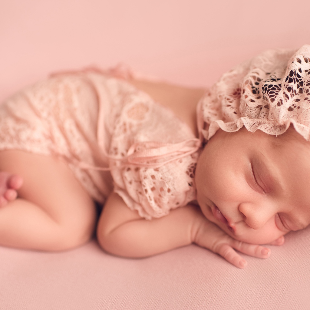 Спящий грудной ребенок в розовом костюме 
