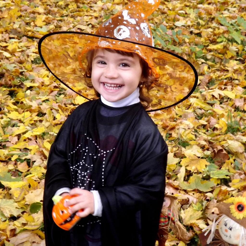 Улыбающаяся девочка в костюме ведьмы на Хэллоуин