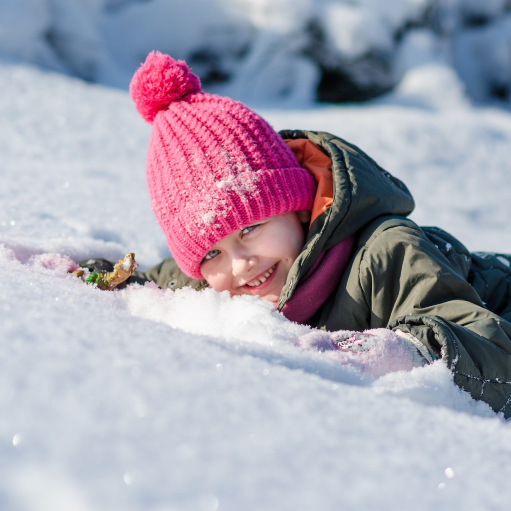 Улыбающаяся девочка лежит на снегу