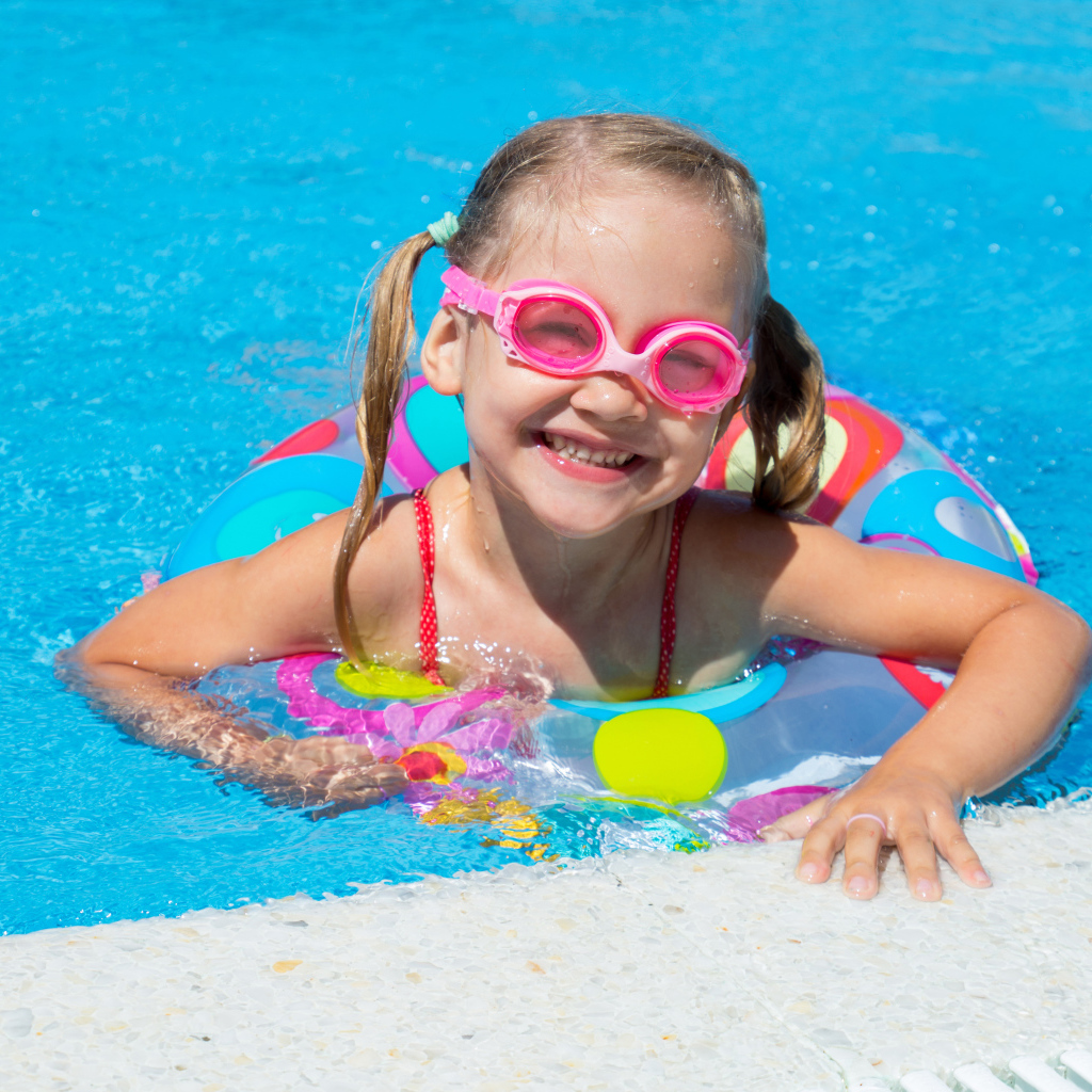 Улыбающаяся девочка с кругом в бассейне 