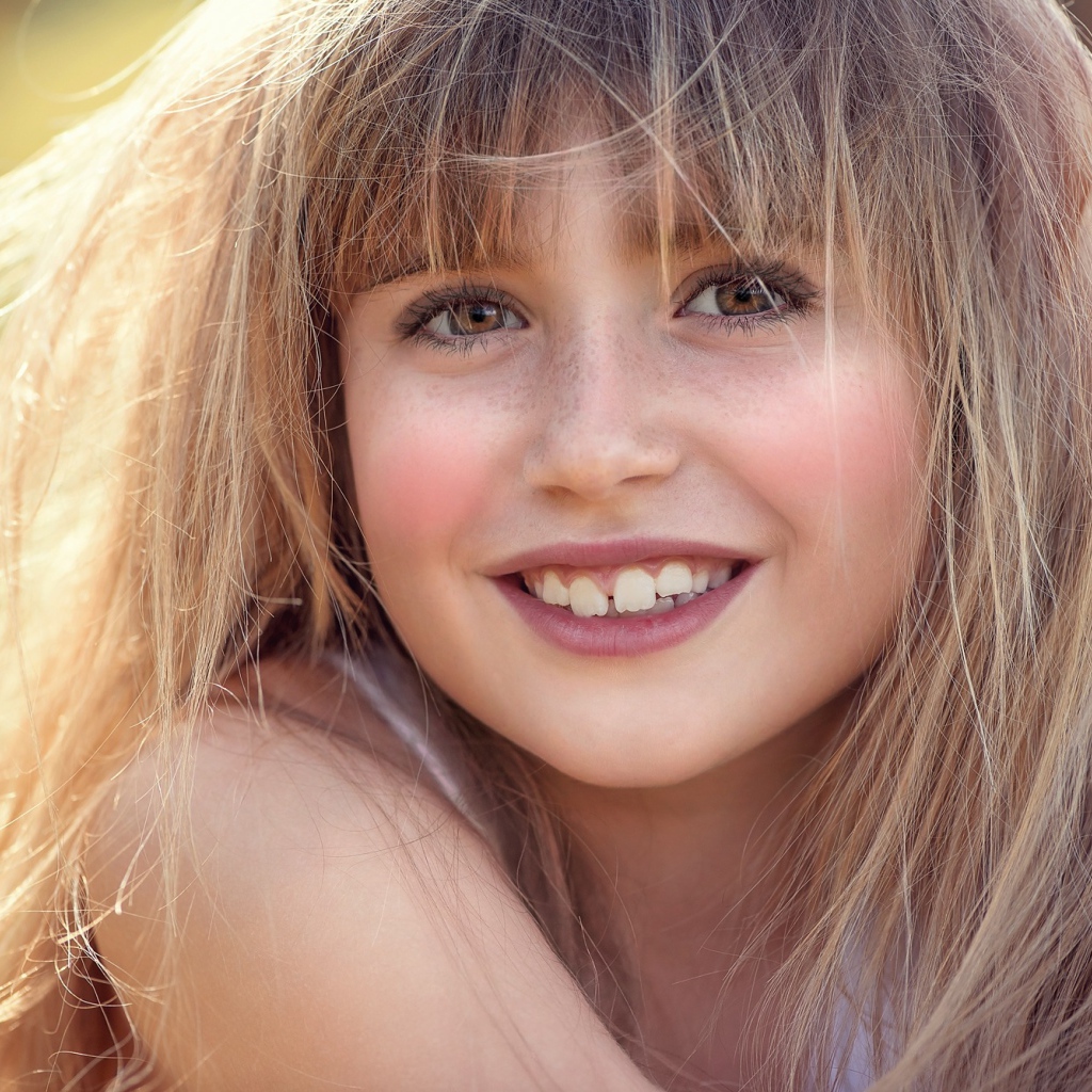 Улыбающаяся девочка с веснушками на лице 