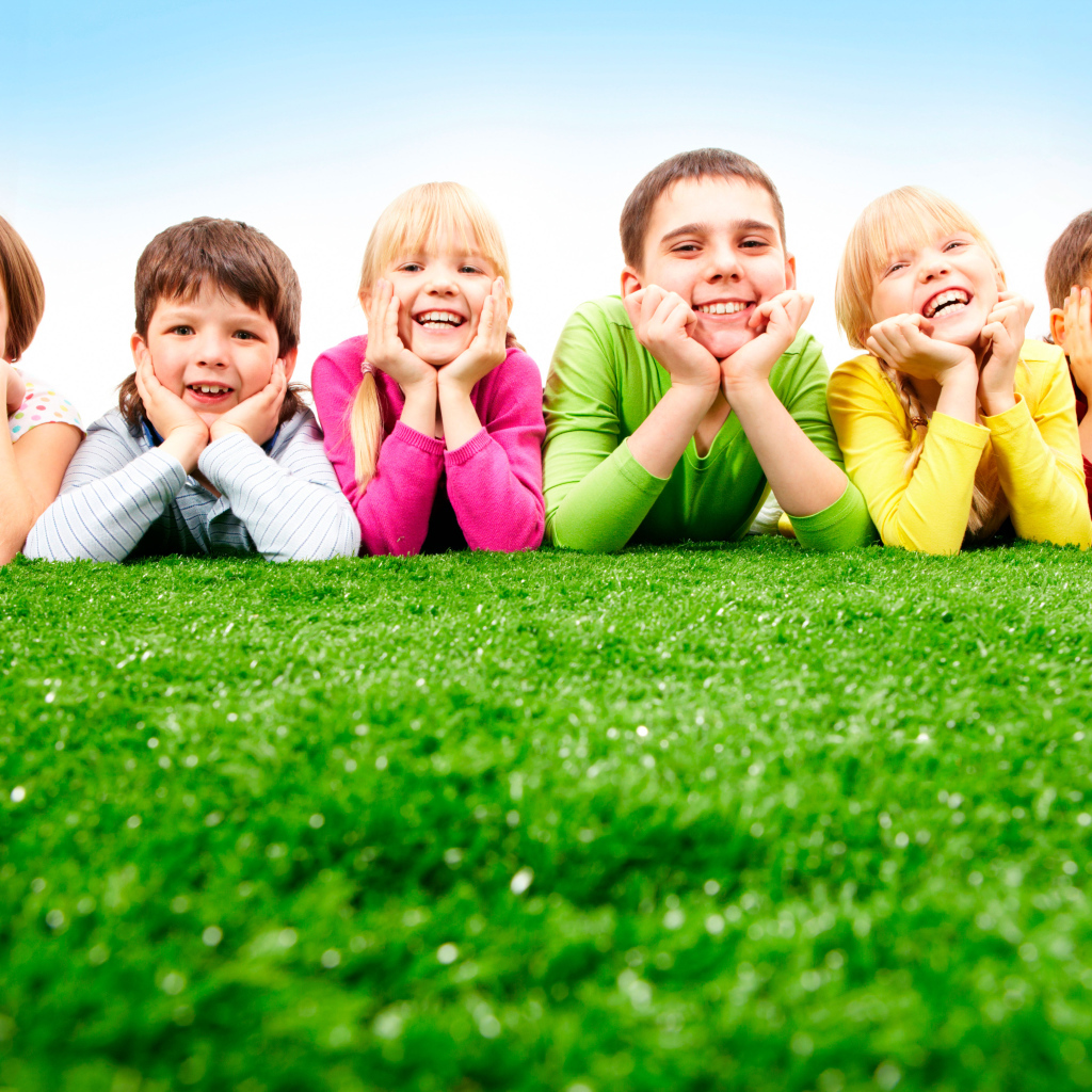 Улыбающиеся дети лежат на зеленой траве