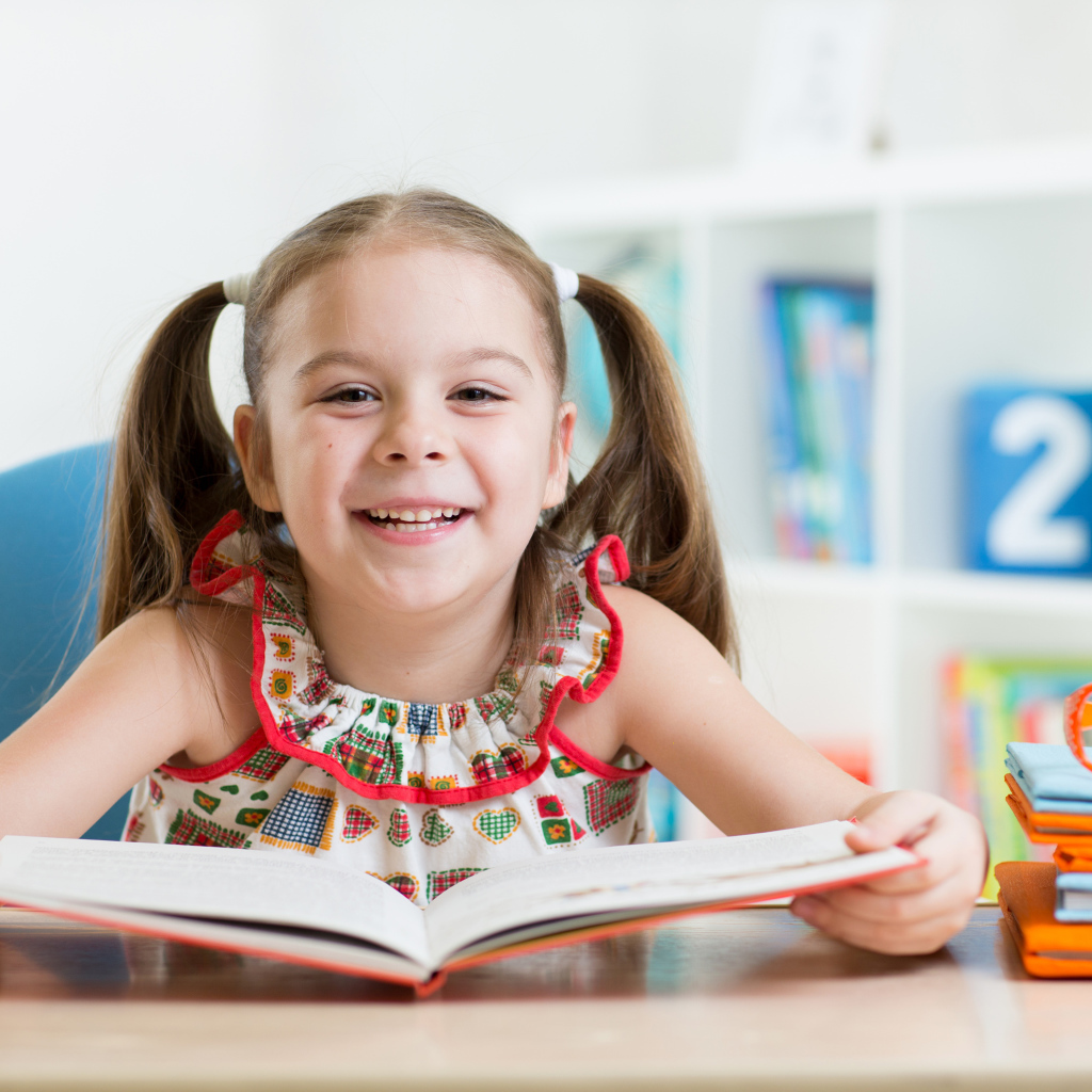 Улыбающаяся маленькая девочка с книгой 