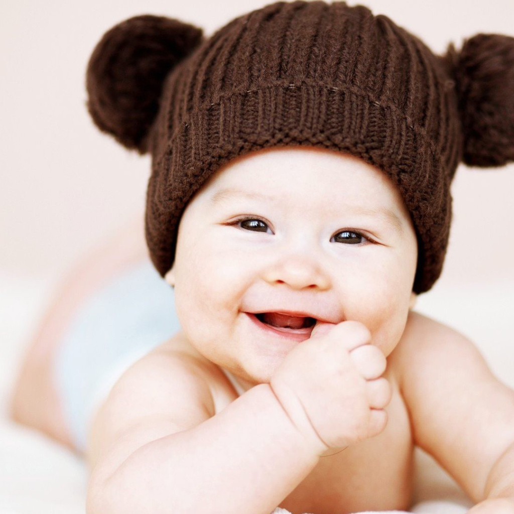 Улыбающийся грудной ребенок в коричневой шапке