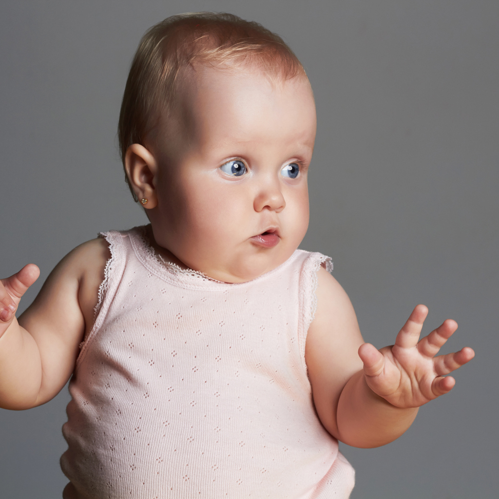 Удивленный маленький ребенок на сером фоне