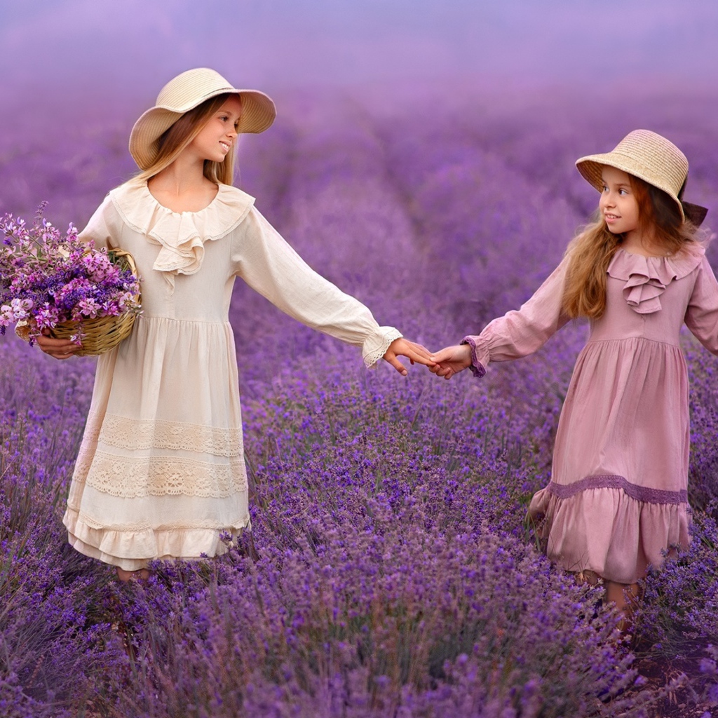 Две маленькие девочки идут по лавандовому полю 