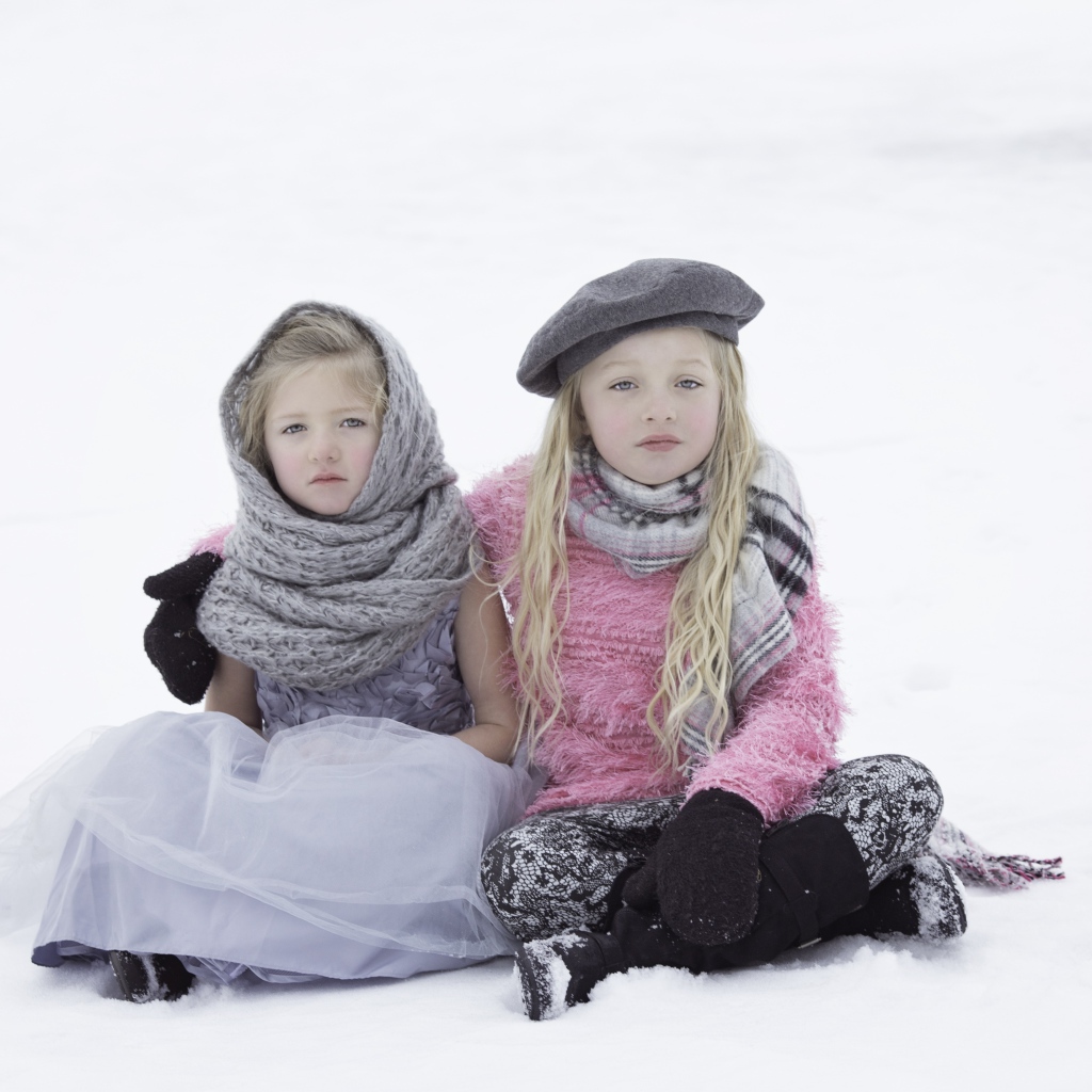 Две маленьких сестры сидят на снегу 