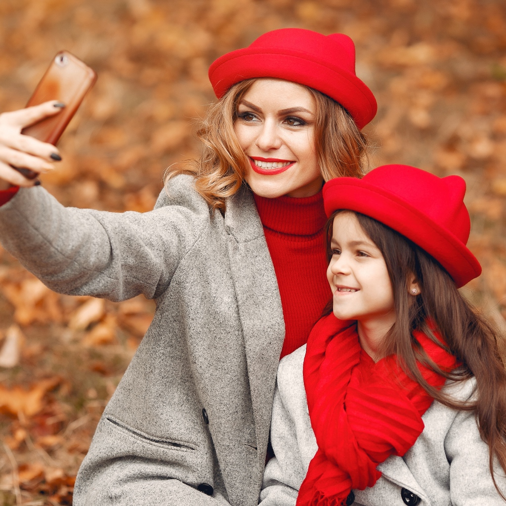 Женщина с маленькой девочкой делают селфи в лесу 