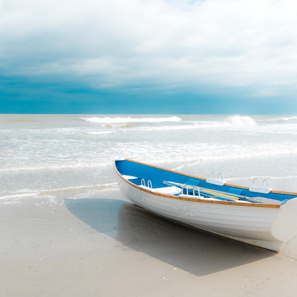 Лодка стоит на белом песке у моря 