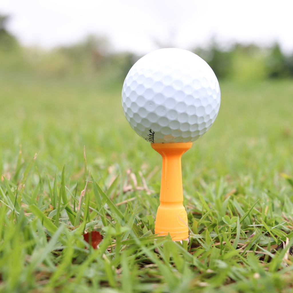 Мячик для гольфа на поле с зеленой травой 