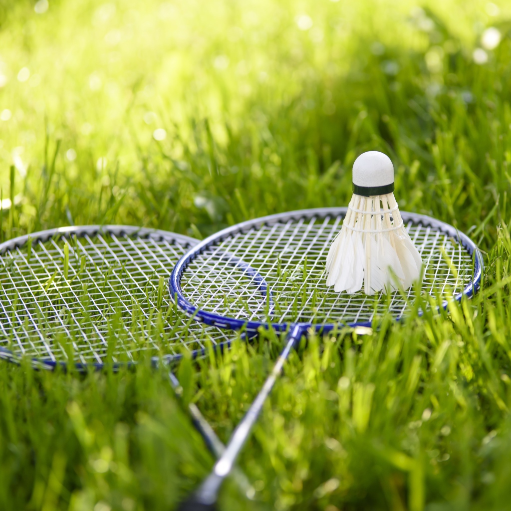 Воланчик и ракетки для игры в бадминтон на зеленой траве