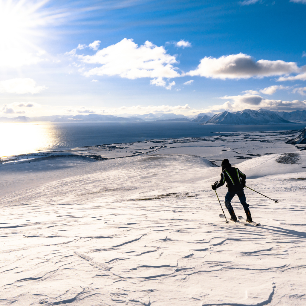 Лыжник едет по снегу под ярким солнцем у воды