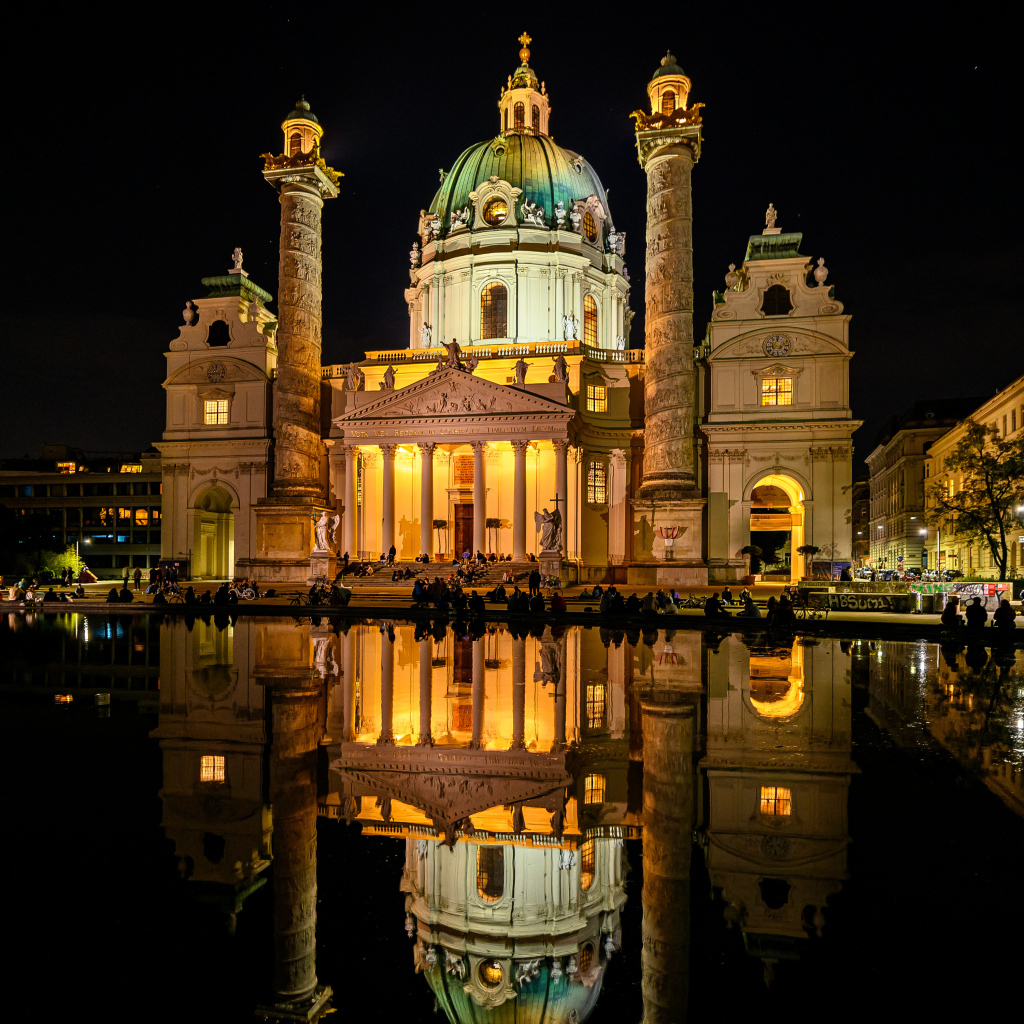 The old Karlskirche church is reflected in the water at night, Vienna. Austria