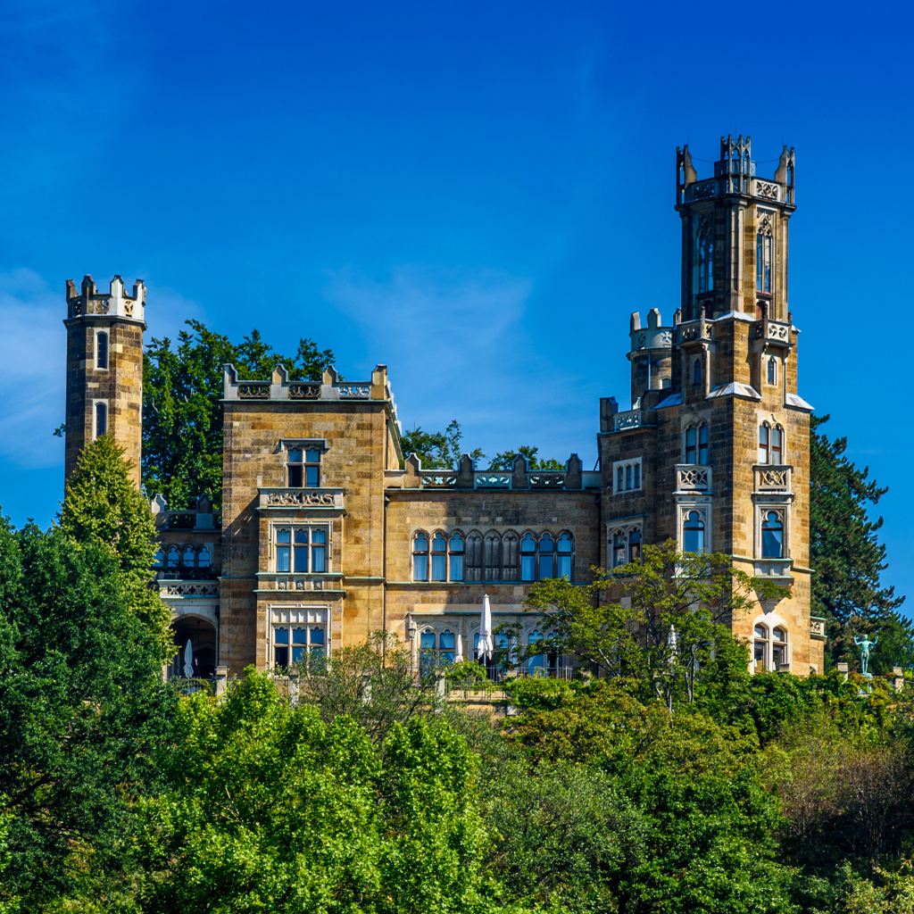 Старинный замок в зарослях деревьев на фоне голубого неба, Германия