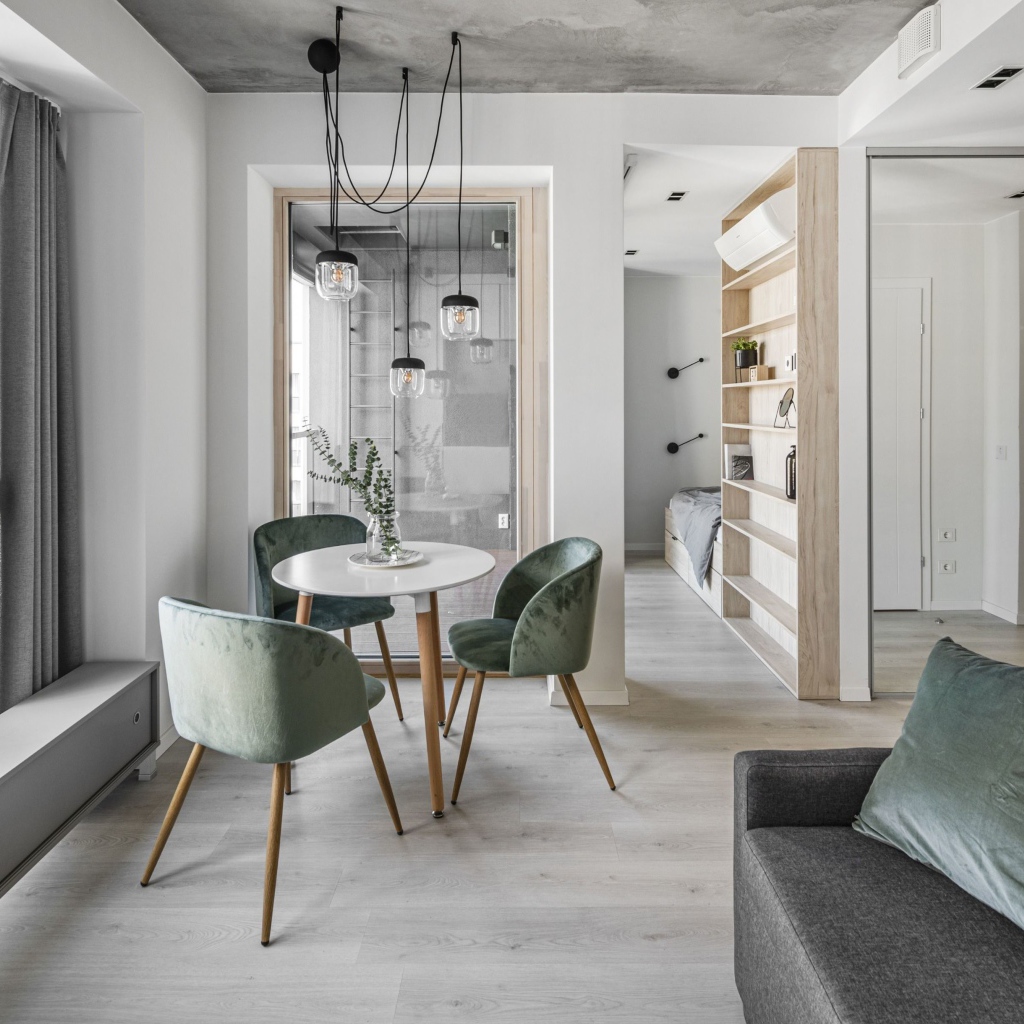 Стол  с креслами стоит у большого окна в квартире 