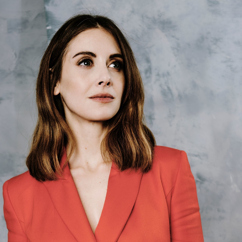 Актриса Элисон Бри в красном пиджаке на сером фоне